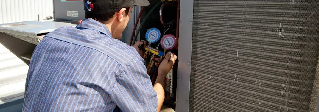HVAC technician servicing a condenser unit in Spencer